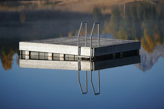 Floating dock with metal ladder on calm water